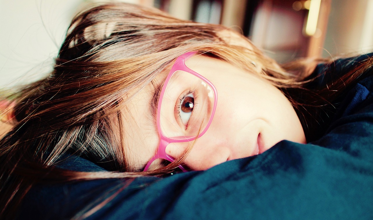A young girl with her head lying sideways on her arms, smiling at the camera