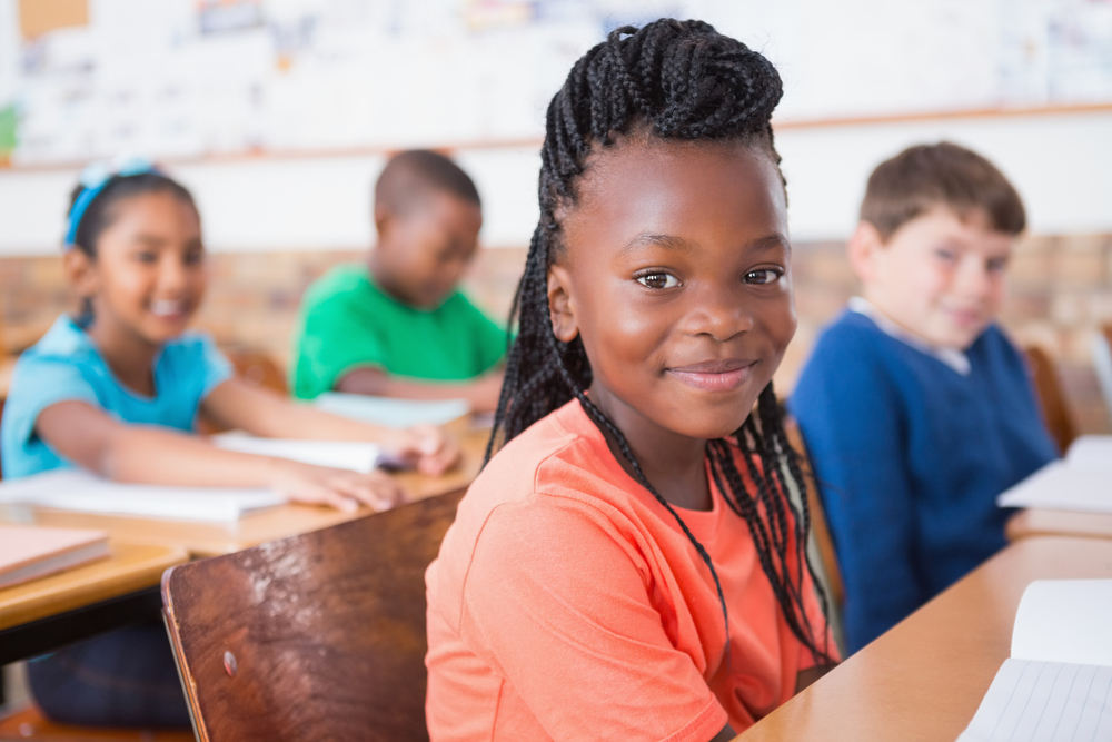 Happy pupils sitting and listening attentively in a classroom